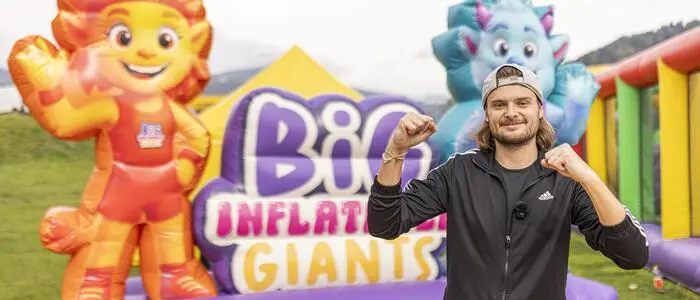 Ein Mann, Anfang 30, steht vor einer Hüpfburg mit der Aufschrift „Big Inflatable Giants“.