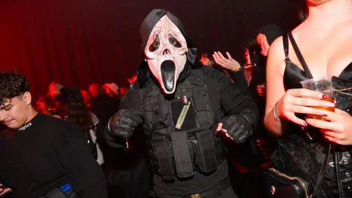 Jemand mit einer Halloweenmaske stehtauf einer Tanzfläche