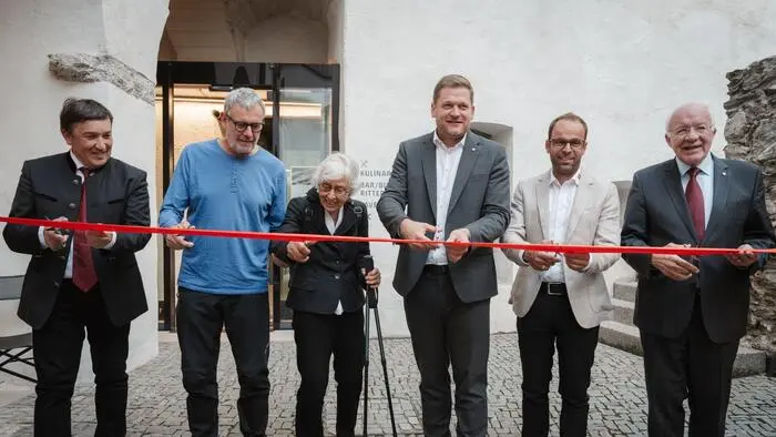 Sechs Personen schneiden ein rotes Band durch