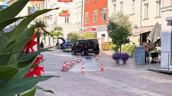 Foto einer mitteleuropäischen Altstadt. Zu sehen sind mehrere orangene Sicherheitshütchen, die frisch verfugte Pflastersteine absperren.