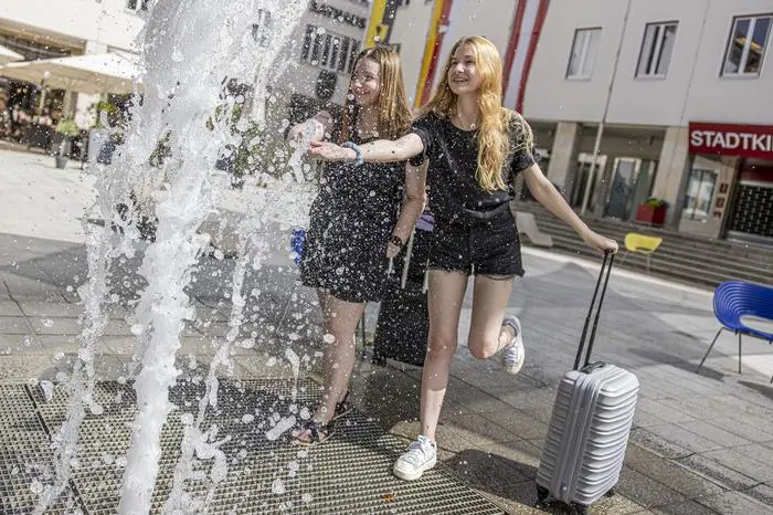 Die Touristinnen Martina und Barbora aus der Tschechischen Republik kühlen sich am Rathausplatz ab