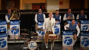 Sieben Musiker auf der Bühne, in der Mitte ein Schlagzeuger, der seinen Schlagstock in die Höhe schmeißt