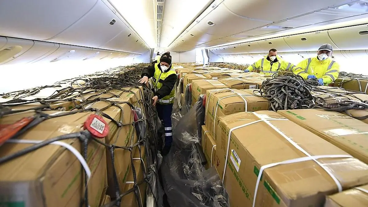 ABD0128_20200330 - SCHWECHAT - ÖSTERREICH: ZU APA0523 VOM 30.3.2020 - Mitarbeiter des Flughafens beim Entladen von Schutzausrüstung aus einer Boeing 777 am Montag, 30. März 2020, am Flughafen Wien-Schwechat. Die Austrian Airlines haben mit zwei zu Frachtflugzeugen umfunktionierten Boeing 777 weitere 30 Tonnen Schutzausrüstung aus China nach Österreich geflogen. Es handelte sich um knapp zwölf Tonnen Masken und knapp 18 Tonnen Mäntel. - FOTO: APA/HELMUT FOHRINGER