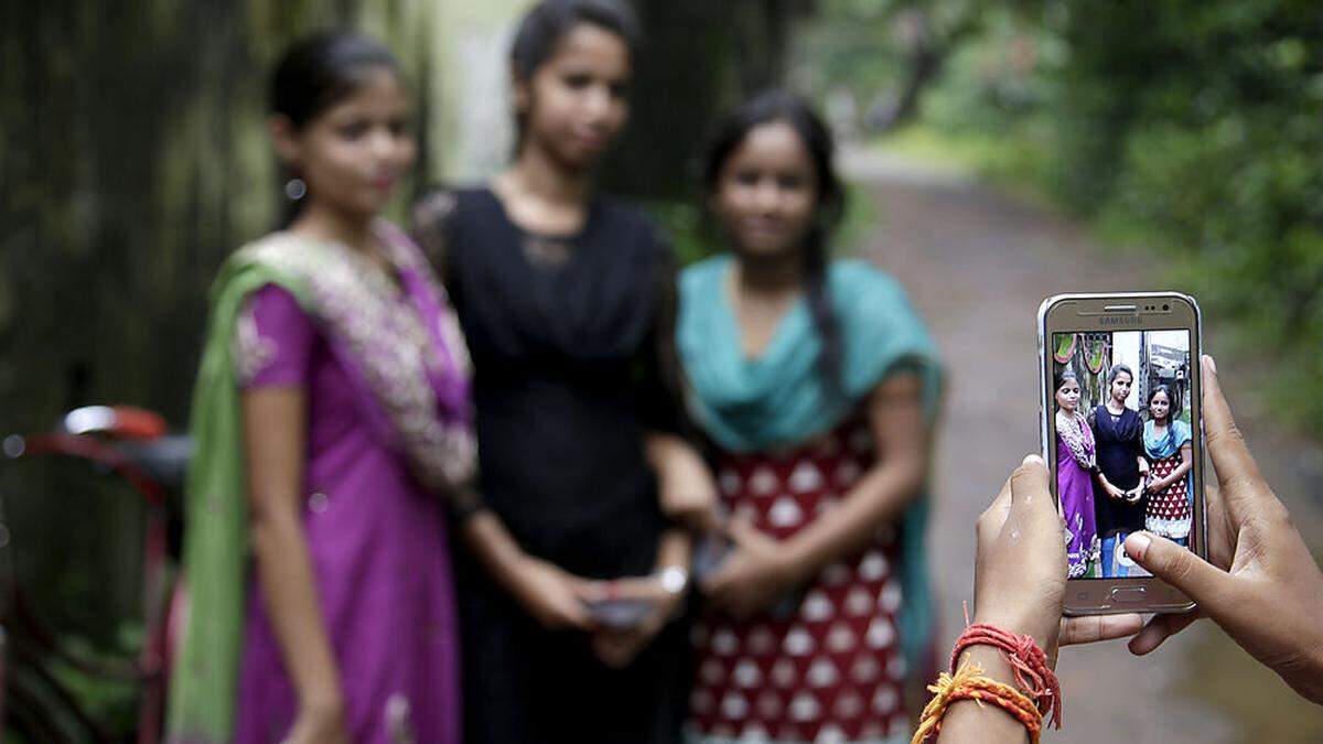 Ein Mädchen nimmt in Indien mit dem Smartphone ein Foto ihrer Freundinnen auf