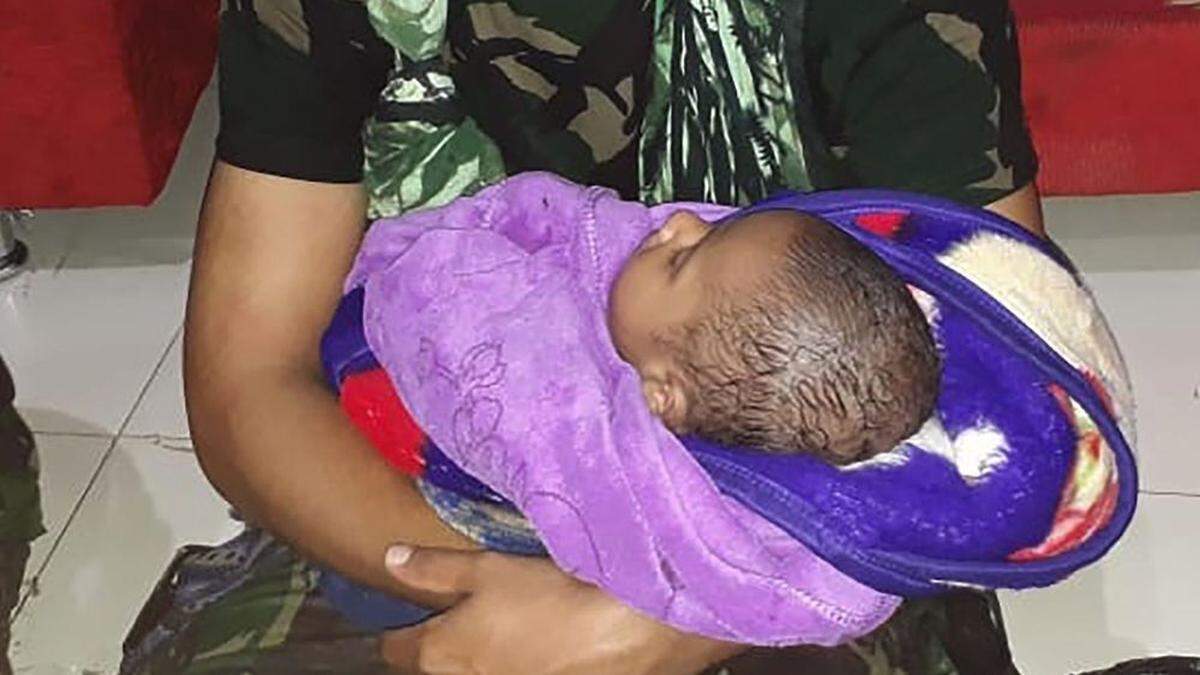 Nach Sturzflut: Baby wieder mit Vater vereint - im Bild das Baby in den Armen eines Soldaten