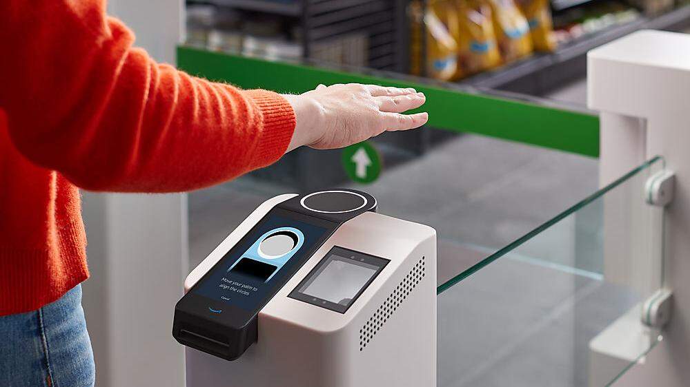 Kunden halten ihre Hände über einen Scanner, der die Handinnenfläche wie einen Fingerabdruck liest