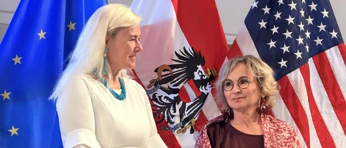 Österreichs Botschafterin Petra Schneebauer steht mit Bürgermeisterin Elisabeth Blanik (SPÖ) vor den Fahnen von Europa, Österreich und der USA