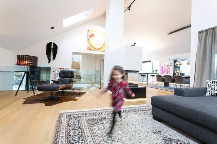 Ikea-Sofa (rechts vorne im Bild) trifft Eames-Lounge-Chair (neben dem offenen Kamin) und Zaha Hadid-Lampe (die "schwarze Fledermaus" im Hintergrund).