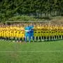 Eine Fußballmannschaft stellt sich für ein Foto auf. Die Spieler tragen gelbe Trikots.