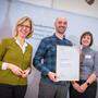 Umweltministerin Leonore Gewessler überreicht Michael Zotter und Christa Bierbaum die Urkunde bei einer Feier in Wien