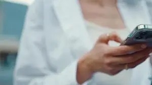 Closeup of young woman holds smartphone in her hands and scrolls through the news feed. Close-up of girl hand uses mobile phone outdoors