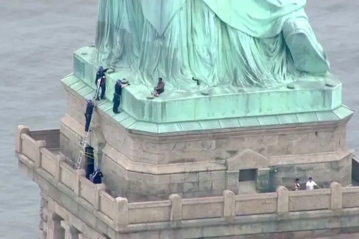 Polizisten bemühten sich, eine Frau, die auf den Sockel der berühmten Statue geklettert war, zur Aufgabe zu bewegen.  