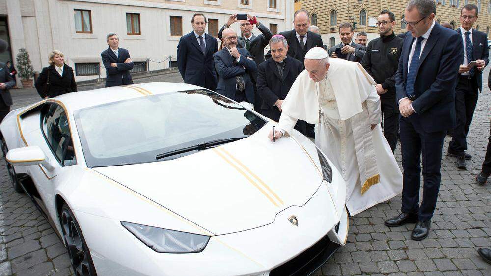 Papst Franziskus beim signieren des Lamborghini