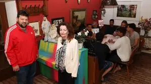 Eine Frau und ein Mann im Vordergrund, dahinter ein Tisch, um den mehrere Männer sitzen