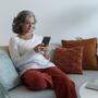 Frau sitzt mit Handy und Laptop auf einem Sofa | Frauen seien laut Justizministerin Zadic besonders häufig von Hass im Netz betroffen.