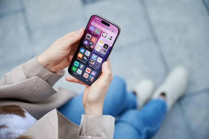 Lviv, Ukraine - October 10, 2024: close up person interacts with smartphone Iphone 16 Pro, navigating home screen filled with apps and widgets, showcasing sleek user interface, personalized features.