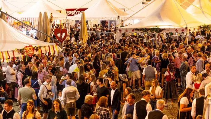 Gedränge auf einem abendlichen Festgelände, im Hintergrund Zelte