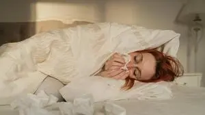 Sick woman rubbing nose with tissue paper lying on bed at home model released, Symbolfoto property released, OSF02524