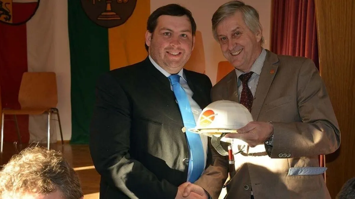 Karl Gerfried Müller (rechts) übergibt  Gerald Ebner (FPÖ) einen Schutzhelm für die politische Zukunft