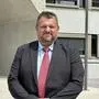 Ein Mann im Anzug steht vor einer Schule