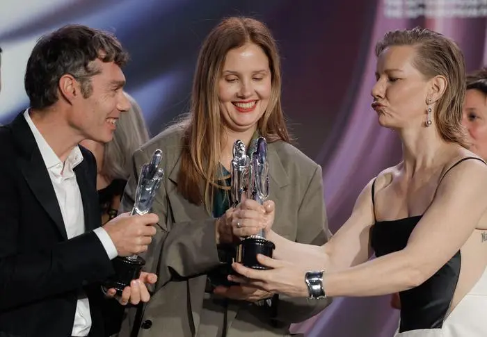 French director Justine Triet (C) and German actress Sandra Hueller (R) and a crew member pose with their three trophies for best 
