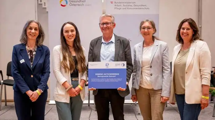 Fünf Menschen stehen nebeneinander und halten ein Schild