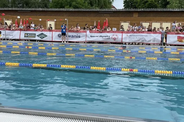 Beim Schwimmwettbewerb haben sich zahlreiche Fans und Besucher rund um das Becken im Freibad versammelt.
