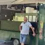 Ein Mann lehnt an einem geöffneten grünen Imbisswagen, daneben steht noch ein Wagen