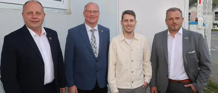 Vier Männer stehen nebeneinander und lachen in die Kamera