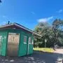 Ein Parkplatz mit einem grünen Toilettenhäuschen