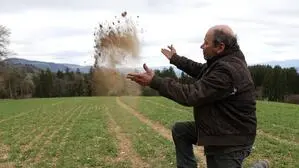 Ein Landwirt wirft Erde in die Luft | Die Trockenheit setzt der Wintergerste von Landwirt Josef Pirker aus Maria Saal zu. 