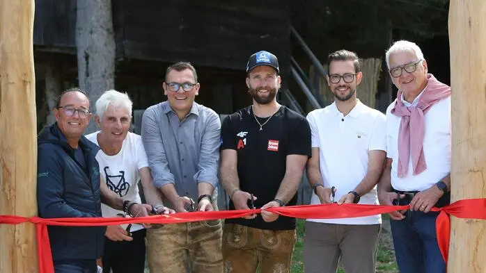 Sechs Männer schneiden ein rotes Band durch