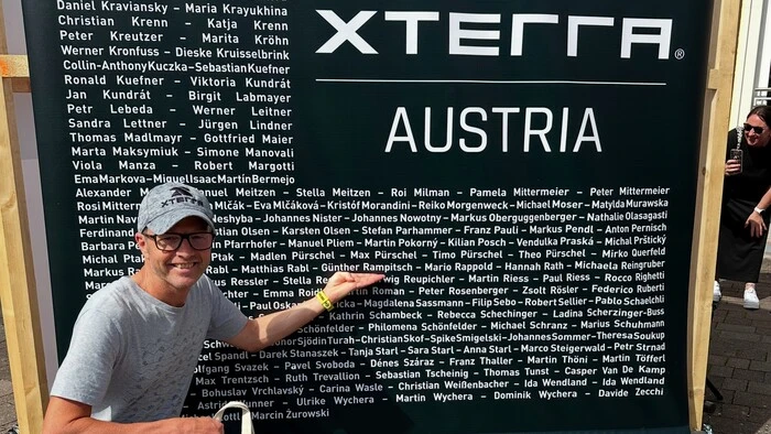 Rampitsch vor einer Tafel mit den Namen aller Teilnehmer beim Xterra Austria