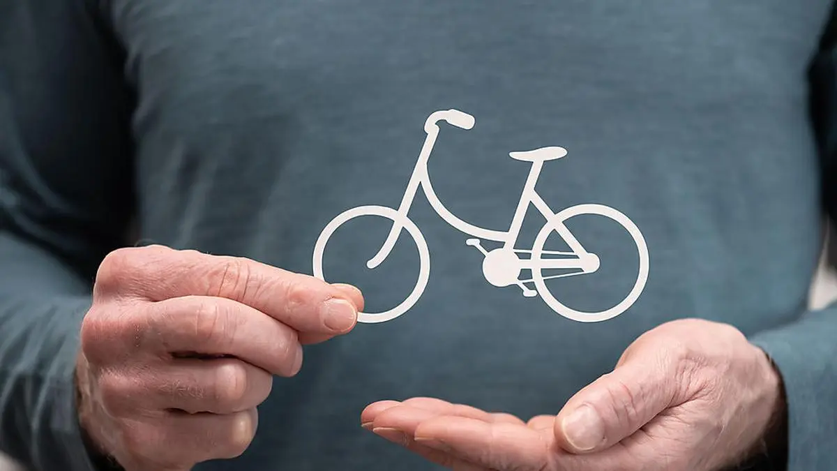 Man holding a paper bicycle; Symbol of bicycle insurance