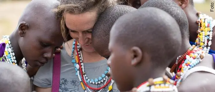 Stephanie Fuchs schaut gemeinsam mit jungen Massai-Frauen Fotos auf dem Handy an