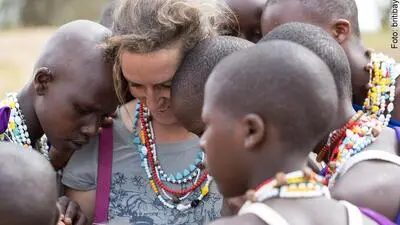 Stephanie Fuchs schaut gemeinsam mit jungen Massai-Frauen Fotos auf dem Handy an 