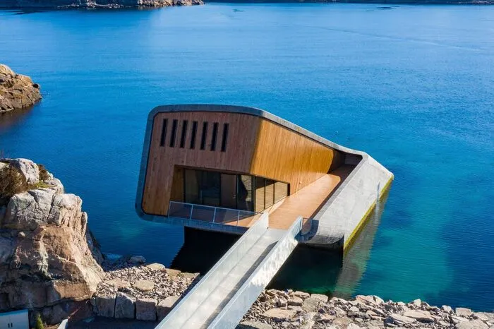 Designt wurde das Restaurant, das diagonal aus dem Wasser ragt, von dem norwegischen Architekturbüro Snøhetta. Sie zeichnen auch für das Opernhaus in Oslo verantwortlich.