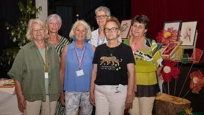 Mehrere Frauen stehen vor Kunstwerken und lachen in die Kamera