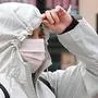 A woman wearing a face mask as a precaution against COVID-19, coronavirus, walks past stores in Monterey Park, California on March 10, 2020. - Los Angeles County announced the first case of COVID-19 through community transmission. (Photo by Frederic J. BROWN / AFP)