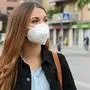 COVID-19 Pandemic Coronavirus Woman in city street wearing KN95 FFP2 mask protective for spreading of disease virus SARS-CoV-2. Girl with protective mask on face against Coronavirus Disease 2019.