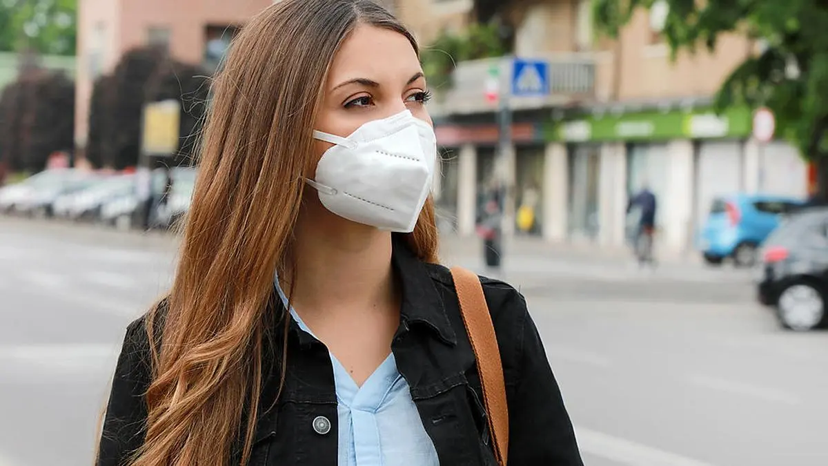 COVID-19 Pandemic Coronavirus Woman in city street wearing KN95 FFP2 mask protective for spreading of disease virus SARS-CoV-2. Girl with protective mask on face against Coronavirus Disease 2019.
