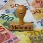 Sujetbild mit Geldscheinen und einem Stempel mit der Aufschrift „Mahnung“