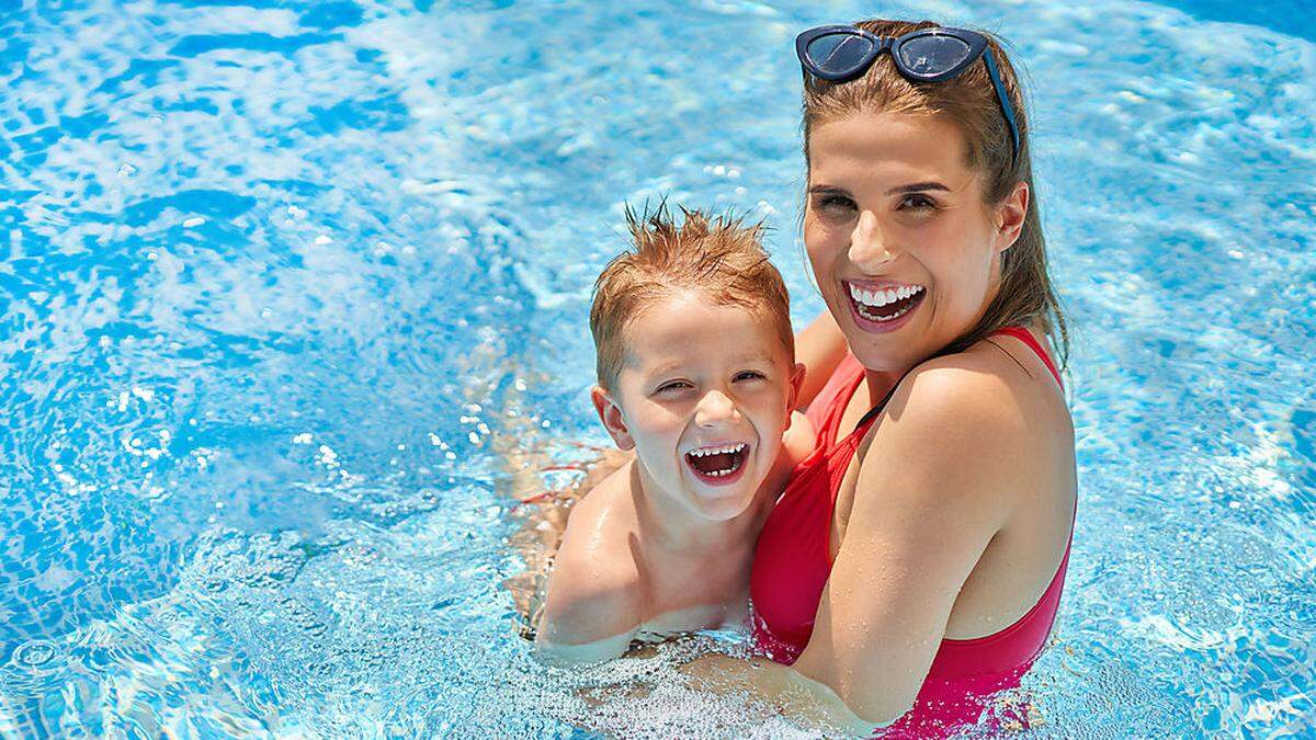 Cute boy with his mother playing in swimming pool during summer