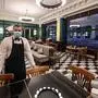 A waiter wearing a protective face mask poses in the nearly empty restaurant "Le Lyrique cafe brasserie" late on May 12, 2020, in Geneva on the day after Switzerland started a second phase to ease lockdown restrictions with school, restaurants, gyms re-open, amid fears of a second coronavirus wave. - Despite being allowed to open again on, many restaurants across Switzerland remained closed - while others were almost empty. (Photo by Fabrice COFFRINI / AFP)