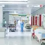 Flur im Krankenhaus mit unscharfem Arzt in Bewegung und Lift rot und Bett