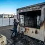 A man takes a photograph of a torched drive-in coronavirus test centre in the port Urk, on January 24, 2021, after youth went on the rampage protesting the first 21:00 night time curfew in the Netherlands since the occupation during World War Two (WWII). (Photo by Jeroen Jumelet / ANP / AFP) / Netherlands OUT