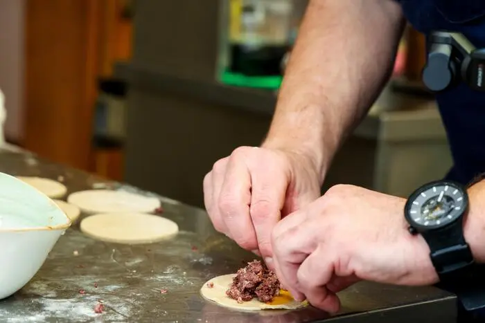 Die Brät der Blutwurst wird in die Teigtaschen gefüllt.