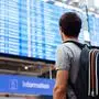 Young man with backpack in airport near flight timetable