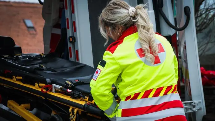 Eine Rettungssanitäterin schiebt eine Trage in einen Rettungswagen