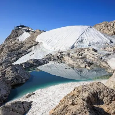 Der Eispalast wird durch eine Polyesterplane geschützt, an seinem Fuß hat sich ein Schmelzwassersee gebildet